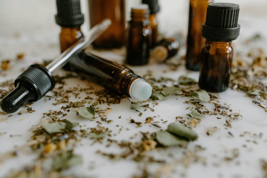 Aromatic essential oils in glass bottles surrounded by natural dried herbs.